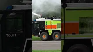 Mollis Airport fire engine passing at full speed with spraying water.