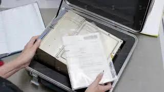 Women's hands are considered from the case. Business woman holding an aluminum briefcase and