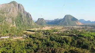 Scenic aerial panorama of sun setting behind Laos mountains creating warm orange glow and stunning