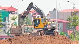 Volvo excavators, dump trucks, road rollers, and cranes are at work.