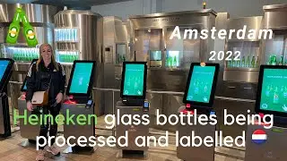 Heineken glass bottles being processed and labelled during the beer production process HD | 2022