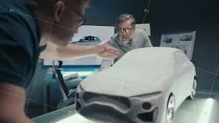 Automotive engineers work in a studio discuss design of prototype car sculpture