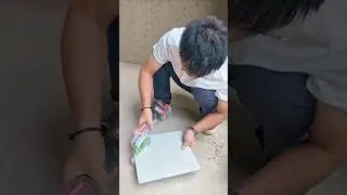 Manually Cutting a Tile with a Cordless Grinder on a Paved Surface