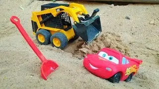 Lightning McQueen - A toy car stuck in the sand.
