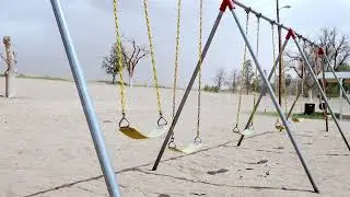 Stock Video - Empty swings moving in slow motion in the wind at a park in Texas