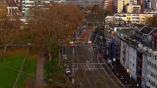 Aerial view tracking an ambulance driving in a German city boulevard, with residential buildings and