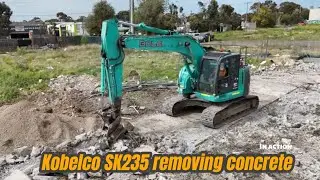 Kobelco SK235 excavator ripping mega concrete and loading a truck