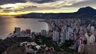sunset cityscape over shimmering water, aerial view showcasing highrise buildings at sunset