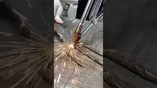 A welding torch is precisely joining metal pieces creating sparks on a wooden surface