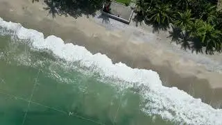Ocean waves at tropical territory with buildings near beach