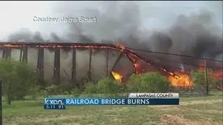 Engulfed railroad bridge crashes to the ground