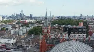 Slide and pan footage of St Pancras train station clock tower. Traffic in streets around. London, UK