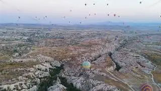 Goreme, Nevsehir, Turkey. Large yellow-blue hot air balloon with fire bursts in foreground flying...