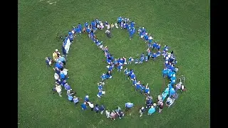 Human Peace symbol formed by kids roughly from 1 to 92