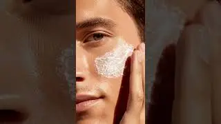 Extreme macro close-up of a male model&rsquo;s cheek and fingers applying thick white creamy skincare m...