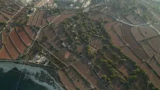 Rural Mediterranean Countryside fly over Brown dry Agriculture Fields revealing Factory by the Water