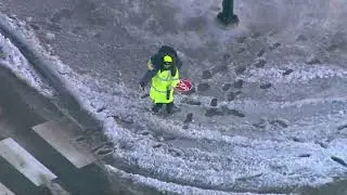 CROSSING GUARD carried a kid on their back across a water soaked Chicago street on this frigid morni