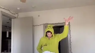 Person in a Grinch onesie wearing a sheet for a kilt.