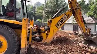Jcb 3dx cleaning land by removing rock pieces and levelling land