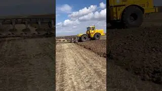 The giant yellow tractor's plough machine was stuck in the field.