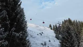 Elevated static view of ski lift gondola transporting people up a snowy mountain slope surrounded by