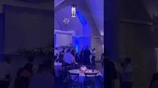 BRIDE ON STAGE SINGING UNWRITTEN TO CROWD WITH UPLIGHTS FLASHING BEHIND HER