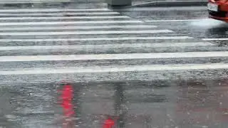 Car splashing water driving crosswalk on a wet urban street during a rainy day