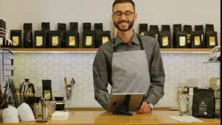 Portrait of male hipster barista using tablet at the work day in the coffee shop and smiling on