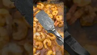 Hand forged one piece grill tongs in use.