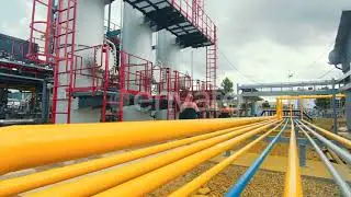 Gasman in a Protective Mask Who Walks Along the Gas Production Station and Inspects It. Yellow G...