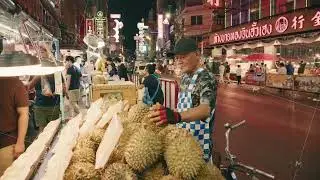Man selling fresh durian fruit from his stall at a busy street market in Bangkok, Thailand. Vibrant