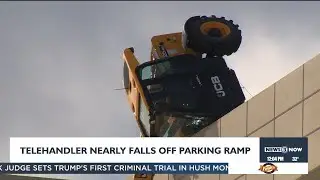 Equipment clearing snow tips over edge of parking ramp