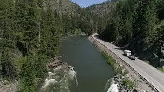 Drone Flying Up Pacific Northwest River With Camper Rv Towing Boat On Mountain Highway | Stock
