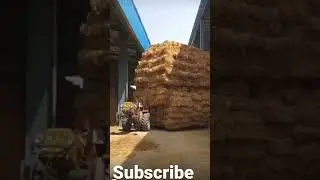 Small tractor pulling huge hay pile