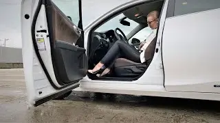 WOMAN DRIVING IN BLACK AND WHITE OUTFIT WITH HIGH HEELS