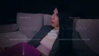 A young adult Caucasian woman is comfortably sitting on her sofa at home and relaxing in the evening