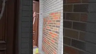 spraying grey paint onto a brown brick wall using professional power spray gun #shorts