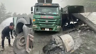 Rescue workers repair a dump truck with a broken front axle at a construction site in the mountains.