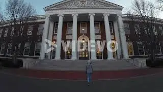 Woman walking towards the entrance of the Baker Library and Bloomberg Center at the business school