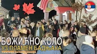 Violina svira Božićno kolo ispred crkve. Narod igra uz plamen Badnjaka.