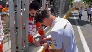 Sebastian Vettel and Lando Norris signing autographs for track marshals