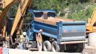 Blue Kenworth Dump Truck dumping dirt on a road construction site