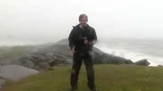 Reporter stands on a cliff in a hurricane