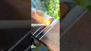worker uses a welding rod to join two metal plates with a bright orange flame