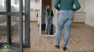 African American woman in oversized jeans looking at dieting success in mirror