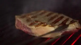 Sizzling steak being seared on a fiery grill at Italian BBQ