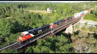 Awesome Aerial 4K View! Big & Fast Stack Train CN 120 w/DPU Crossing Bridge at Oxford Junction, NS