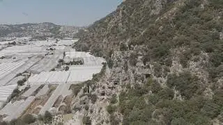 D-Log M. Demre, Turkey. Aerial drone view of ancient Lycian rock-cut tombs in cliff with vast whi...