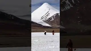 Tibetan girls play football against the backdrop of snow-capped mountains in winter