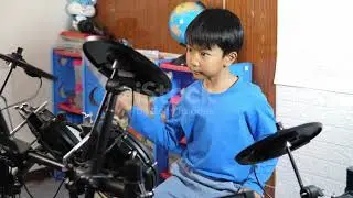 Asian child boy play electronic drum. Kid show drum music at home with happy relax face.